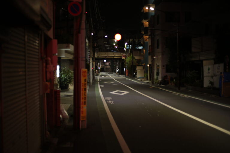 Liminal night street in Japan with closed shutters and empty lane markings