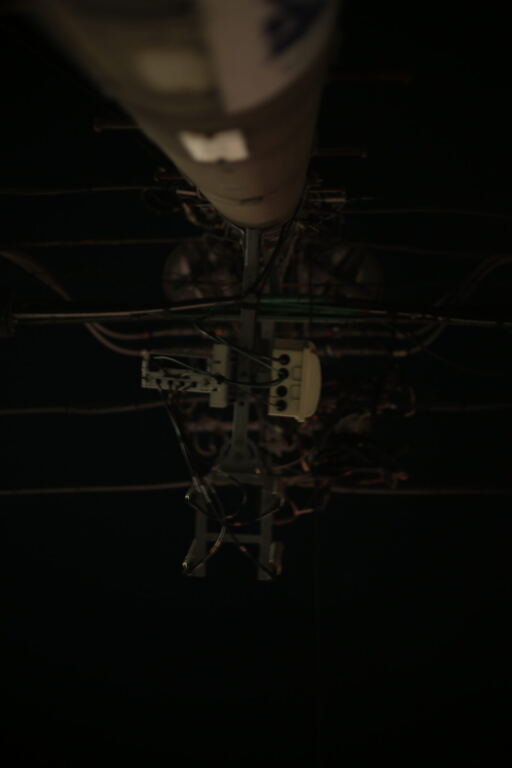 Utility pole and cables rising into a black night sky, photographed vertically