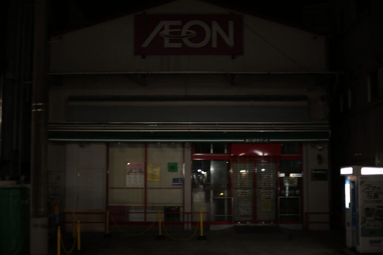 Closed convenience store entrance at night with dim signage and shuttered doors