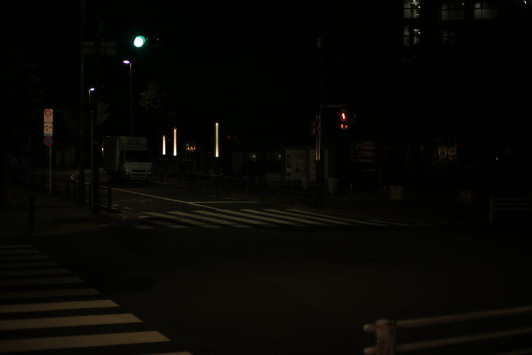 Dark multi-lane intersection with zebra crossings and sparse streetlights