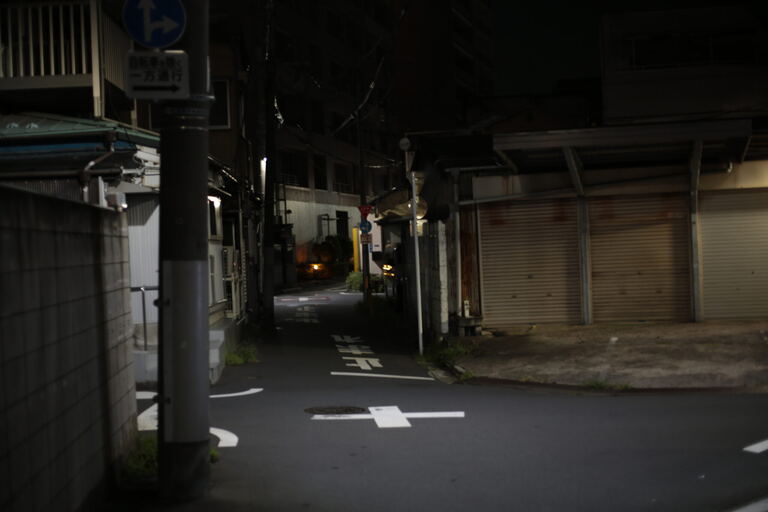 Narrow side street with shuttered shops and painted directional arrows at night