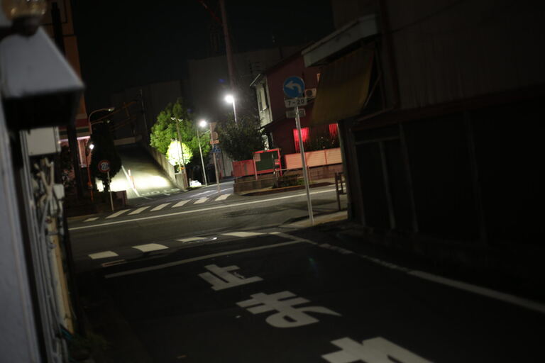 Steep residential night street lit by a few lamps at an empty intersection