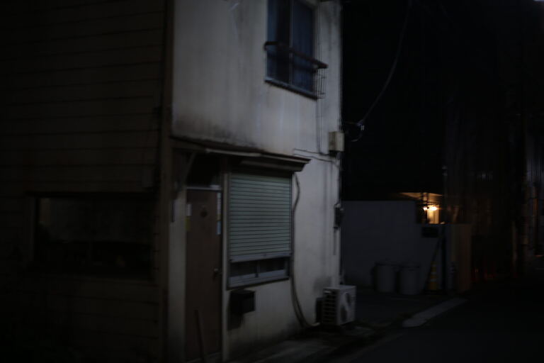 Quiet alley beside an apartment facade with one warm window light